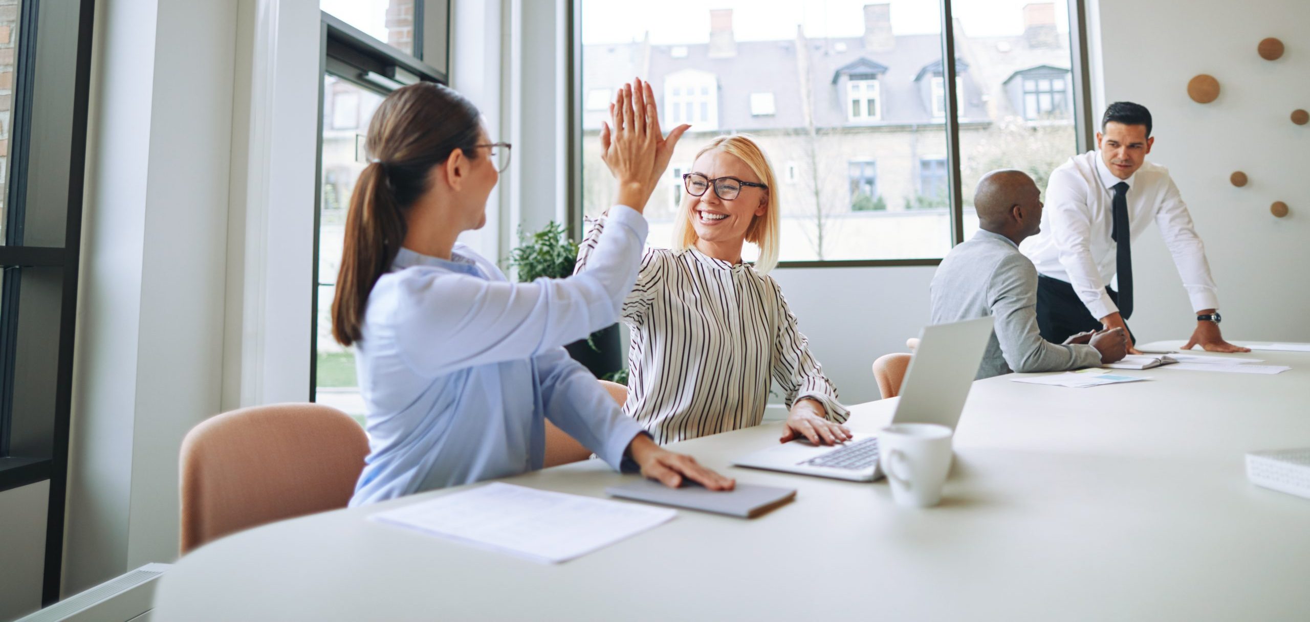 Smiling businesswomen high fiving each other in an office boardroom